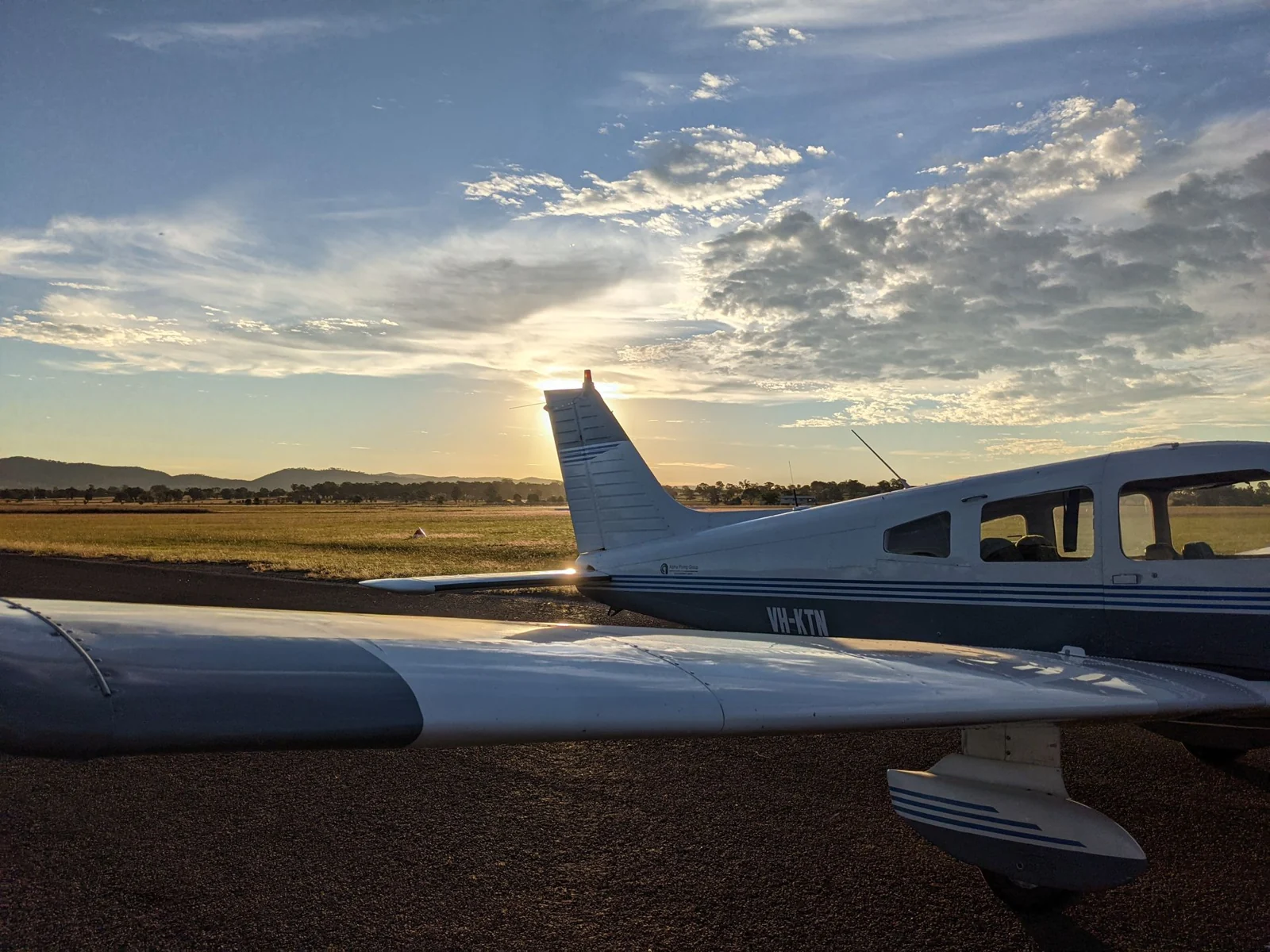 VH-KTN in evening light at Mudgee, with sunlight behind the tail and its wing in the foreground